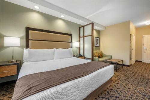 a hotel room with a large bed and a chair at Best Western Plus College Park Hotel in College Park