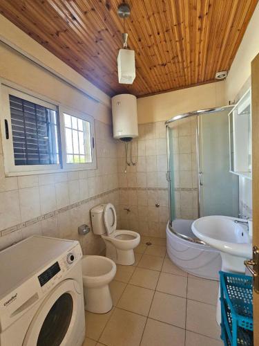 a bathroom with a toilet a sink and a washing machine at La Piscina in Shkodër