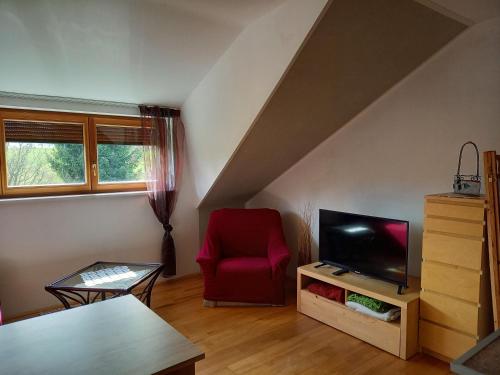a living room with a red chair and a television at Ferienwohnung in Haidach in Pettighofen