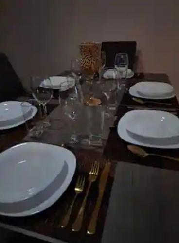 a wooden table with white plates and forks and glasses at Depa Santorini in Veracruz