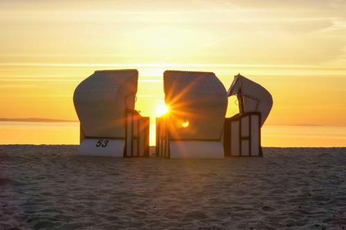 a sunset on the beach with a couple at Haff-Ostseeferienhaus Nebengebäude in Mönkebude