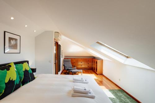 una camera bianca con un letto e un soffitto spiovente di Home Out Casa do Arco in Belém a Lisbona