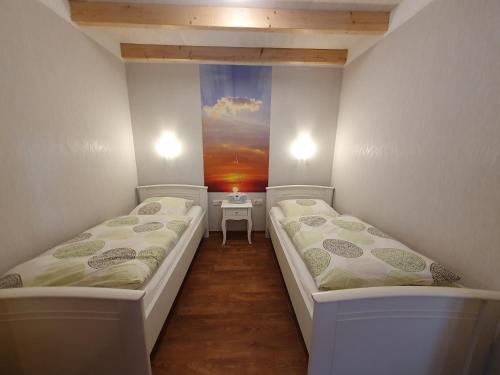 two beds in a room with a painting on the wall at Ferienobjekte Claus, 35633 in Uplengen
