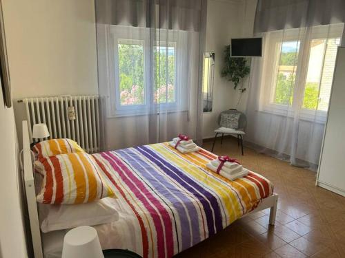 a bedroom with a bed with a colorful blanket and windows at Casa Giacinti in Falerone