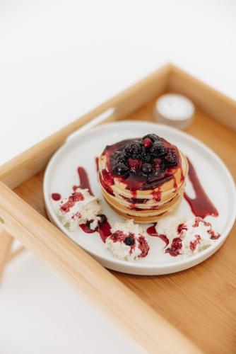 a plate with a stack of pancakes with syrup and fruit at Centoquindici Rooms & Suite in Montesilvano