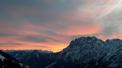 a sunset over a mountain range with snow covered mountains at Haus Lukasser in Assling