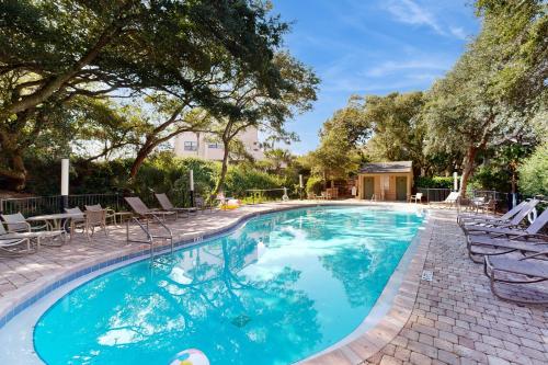 フェルナンディーナ・ビーチにあるGround-floor summer beach village condo with a great view plus patio & poolの木々のあるスイミングプール(椅子、テーブル付)