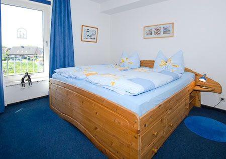a bedroom with a wooden bed in front of a window at Haus Hafenblick in Bensersiel