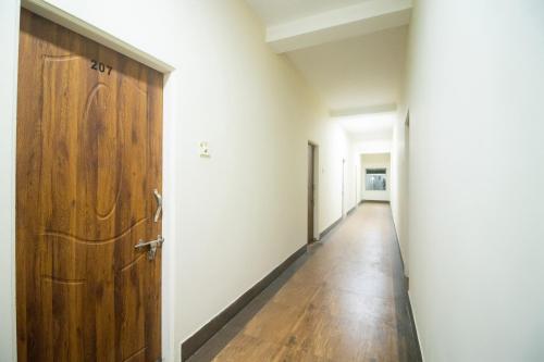 an empty corridor with a wooden door in a room at Hotel O Prabir Residency Inn in Urāli