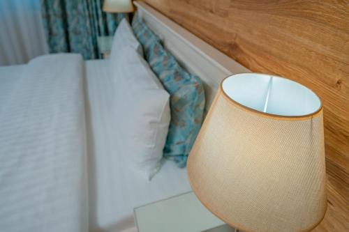 a lamp sitting next to a white bed at Pensiunea Ovidiu in Crisan