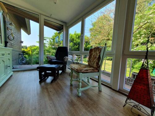a living room with two chairs and windows at Ferienwohnung Am Traumgarten, 35646 in Uplengen