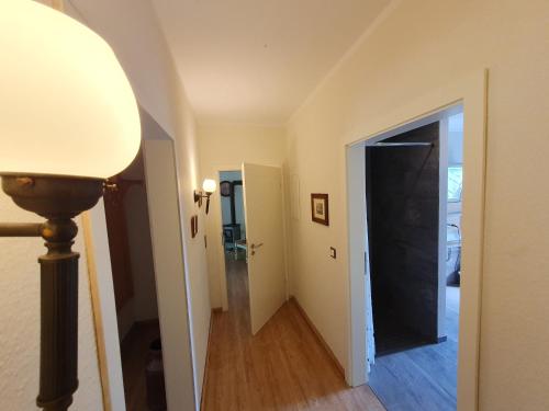 a hallway with a lamp and a hallway leading to a door at Ferienwohnung Am Traumgarten, 35646 in Uplengen