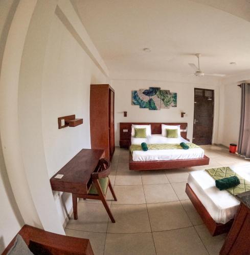 ヒッカドゥワにあるTraveller's Hotel Hikkaduwaのベッドと机とソファのある寝室