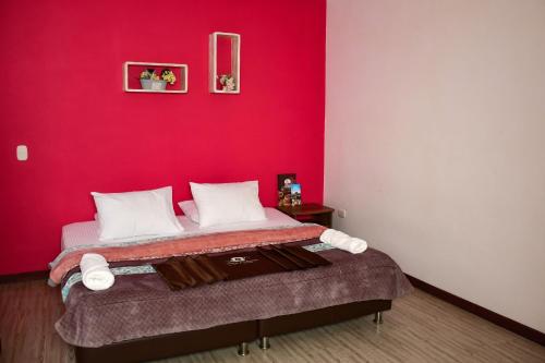 a bedroom with a bed with a red wall at Hotel Villa Colonia in Marinilla