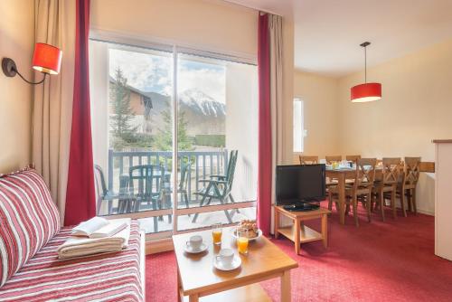 un salon avec un canapé et une grande fenêtre dans l'établissement Résidence Pierre & Vacances Les Rives de l'Aure, à Saint-Lary-Soulan