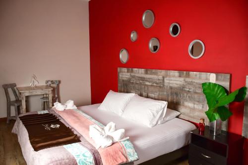 a bedroom with a bed with a red wall at Hotel Villa Colonia in Marinilla