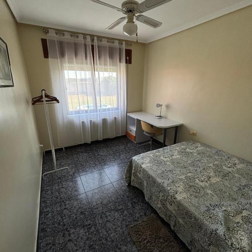 a bedroom with a bed and a desk and a window at Casa cómoda, amplia y tranquila 