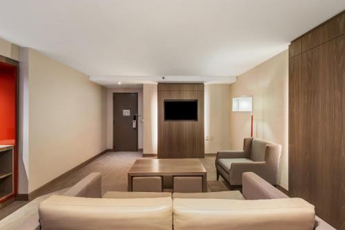 a living room with a couch and chairs and a tv at InterContinental São Paulo by IHG in Sao Paulo