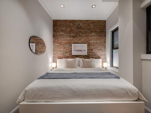 a bedroom with a brick wall and a large bed at Two-Bedroom Sutton Place Condo-Hotel in New York