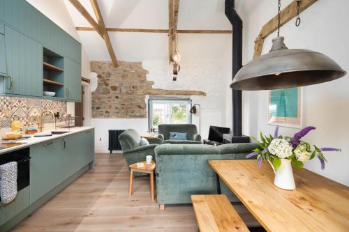 a kitchen and living room with green furniture and a table at Cwm Connell Coastal Cottages in Moylgrove