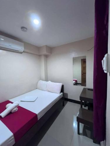 a white room with a bed and a mirror at WJV Inn Bohol in Tagbilaran City