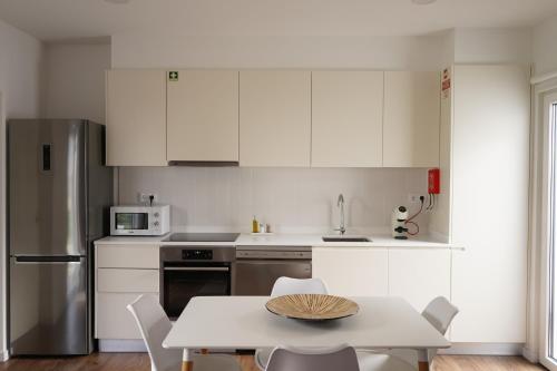 a kitchen with white cabinets and a table with chairs at Vilas do Olival in Ponta Delgada
