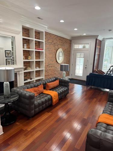 a living room with a leather couch and a brick wall at Classy Victorian Brownstone Subway Shopping in Washington, D.C.