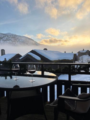two glasses of wine sitting on a table on a balcony at Apartment vårstølen - myrkdalen skisenter in Vossevangen