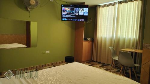 a bedroom with a bed and a tv on the wall at Hostal Residencial Mochica in Lima