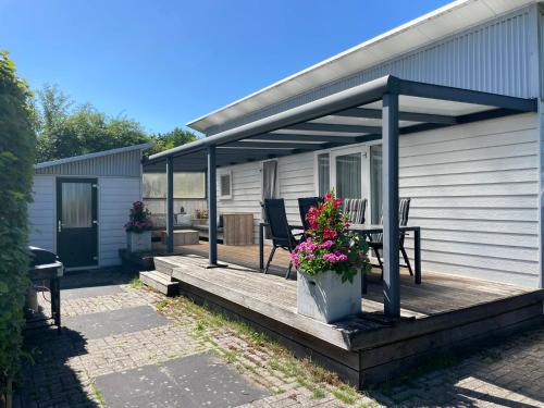 a deck with chairs and flowers on a house at Chalet op Camping in het Drents Friese Wold in Oude Willem