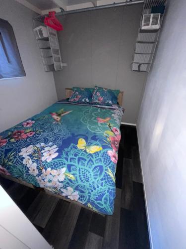 a small bedroom with a bed with a colorful comforter at Chalet op Camping in het Drents Friese Wold in Oude Willem