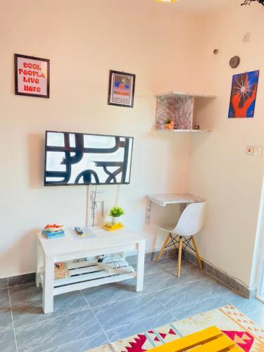 a living room with a white table and a chair at Fk homes executive studio with rooftop pool in Mtwapa