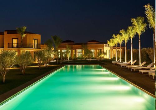 a swimming pool with palm trees in front of a house at Vizir 301 in Marrakech