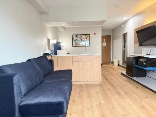 a living room with a blue couch and a kitchen at Microtel Inn & Suites by Wyndham Sioux Falls in Sioux Falls