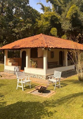 ein kleines Haus mit zwei Stühlen und einer Feuerstelle in der Unterkunft Casa de Campo com Lago e Jardim - Pet-Friendly in Miguel Pereira