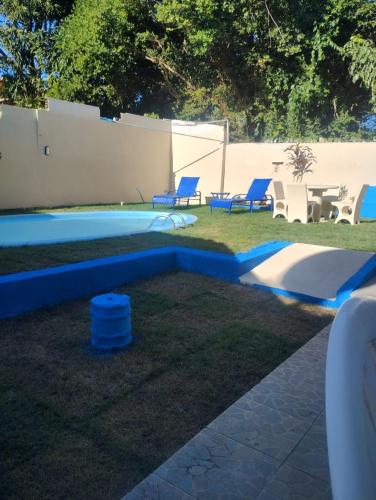a backyard with a pool with blue chairs and a table at Bromelias Imbassai in Imbassai