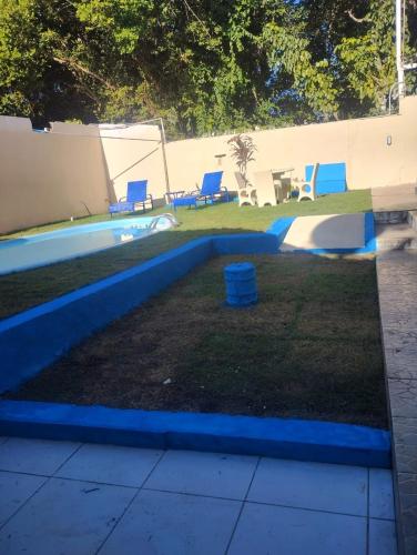 a pool in a yard with blue chairs next to it at Bromelias Imbassai in Imbassai