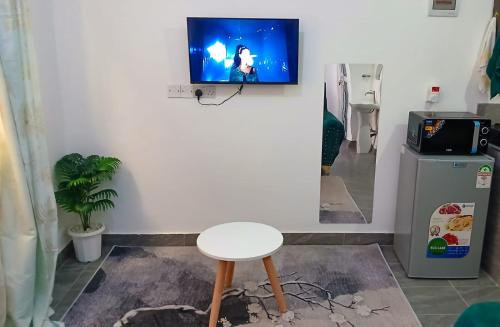 a table and a stool in a room with a tv on the wall at Fk homes executive studio with rooftop pool in Mtwapa