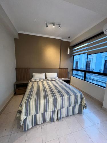 ein Schlafzimmer mit einem Bett und einem großen Fenster in der Unterkunft Apto de 2 habitaciones en el centro de Tarija! in Tarija