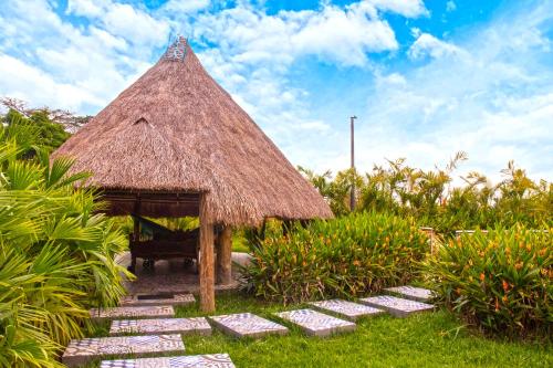a small hut with a grass roof and some plants at Villa Teresita Campestre in Estación El Salto