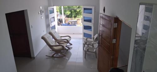 a hallway with three rocking chairs in a room at hospedaje liwa casa de paso in Mangue