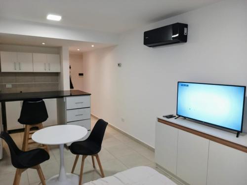 a kitchen with a table and chairs and a flat screen tv at Temporary Rental in Chivilcoy