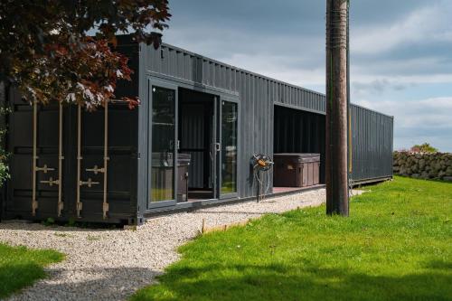 a black building with glass doors and a pole at The Brambles Retreat in the Mournes in Annalong