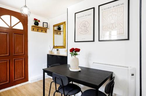 a black dining room table with black chairs and a vase with flowers at Maison Cosy Paisible avec Jardin in Livry-Gargan