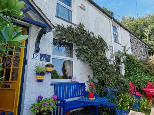 un banc bleu devant une maison dans l'établissement Fantastic sea views at Century's old Alma's Cottage - Sleeps up to 8 guests, à Penmaen-mawr