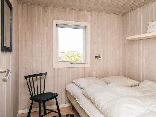 a bed in a room with a chair and a window at 6 person holiday home in Hjørring in Lønstrup