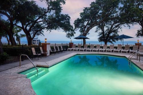 a swimming pool with chairs and umbrellas at The Inn at Long Beach in Long Beach