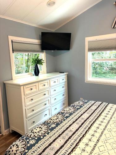a bedroom with a bed and a dresser with a tv at River Run Cottage Modern 2BR Waterfront Retreat in Linville Land Harbor in Newland
