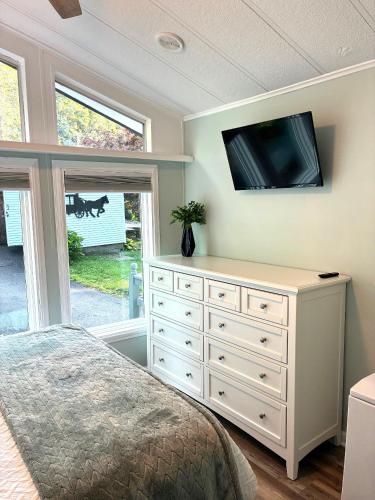 a bedroom with a dresser with a tv on the wall at River Run Cottage Modern 2BR Waterfront Retreat in Linville Land Harbor in Newland
