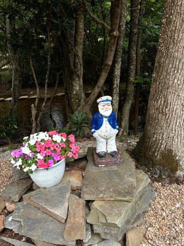 a statue sitting on rocks next to a pot of flowers at River Run Cottage Modern 2BR Waterfront Retreat in Linville Land Harbor in Newland